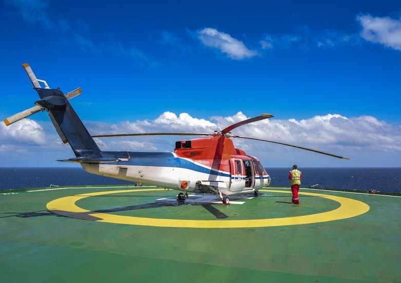 Cheif of helipad jack up oil rig crew walk around to check helicopter before departure